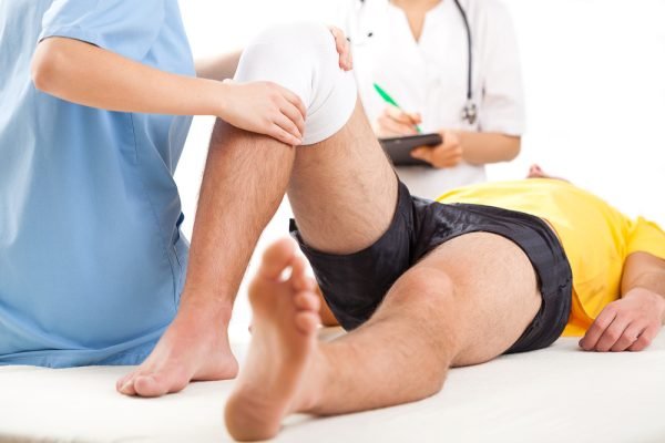 Qualified medical team examining knee condition in clinic for athletes.